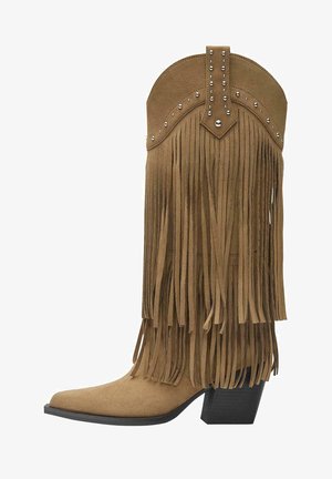 Botte de cowboy en daim beige avec des franges superposées, des clous métalliques sur le haut, un bout pointu et un talon empilé noir.