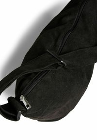 Crna suede torba s patentnim zatvaračem, koja se odlikuje glatkom teksturom, zaobljenim oblikom i tankim, podesivim remenom.