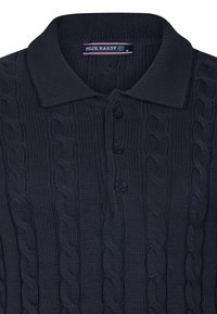Tumesinine kootud polo särk, millel on nööbid, kaelus ja tekstiilimineku muster. Etiketil tekst "FELIX HARDY", suurus M.