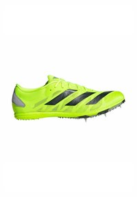 Scarpe da ginnastica verdi e brillanti con una tomaia in rete, strisce nere e punte metalliche sulla suola per una migliore trazione sulle superfici della pista.