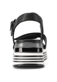 Infradito in pelle nera con una larga strap, caratterizzate da una suola a piattaforma a righe in bianco e nero e un accento metallico sul tallone.