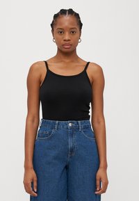 Svart tettsittende tank topp med tynne stropper, kombinert med høyt liv blå denim jeans med rette ben og frontlommer.