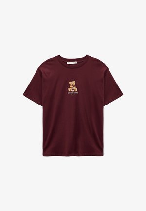 T-shirt en coton bordeaux avec un motif d'ours et le texte « BUT FIRST COFFEE » en dessous. Manches courtes, col rond, coupe décontractée.