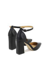 Scarpe con tacco alto nere in materiale sintetico, con punta affusolata, cinturino alla caviglia e tacco quadrato spesso. Texture liscia con una fodera beige.