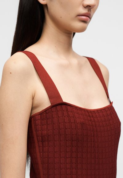 Τοπ σε χρώμα σκουριάς με υφασμένο τετράγωνο μοτίβο, λεπτές τιράντες και εφαρμοστή σχεδίαση, κατάλληλο για καθημερινές ή επίσημες περιστάσεις.