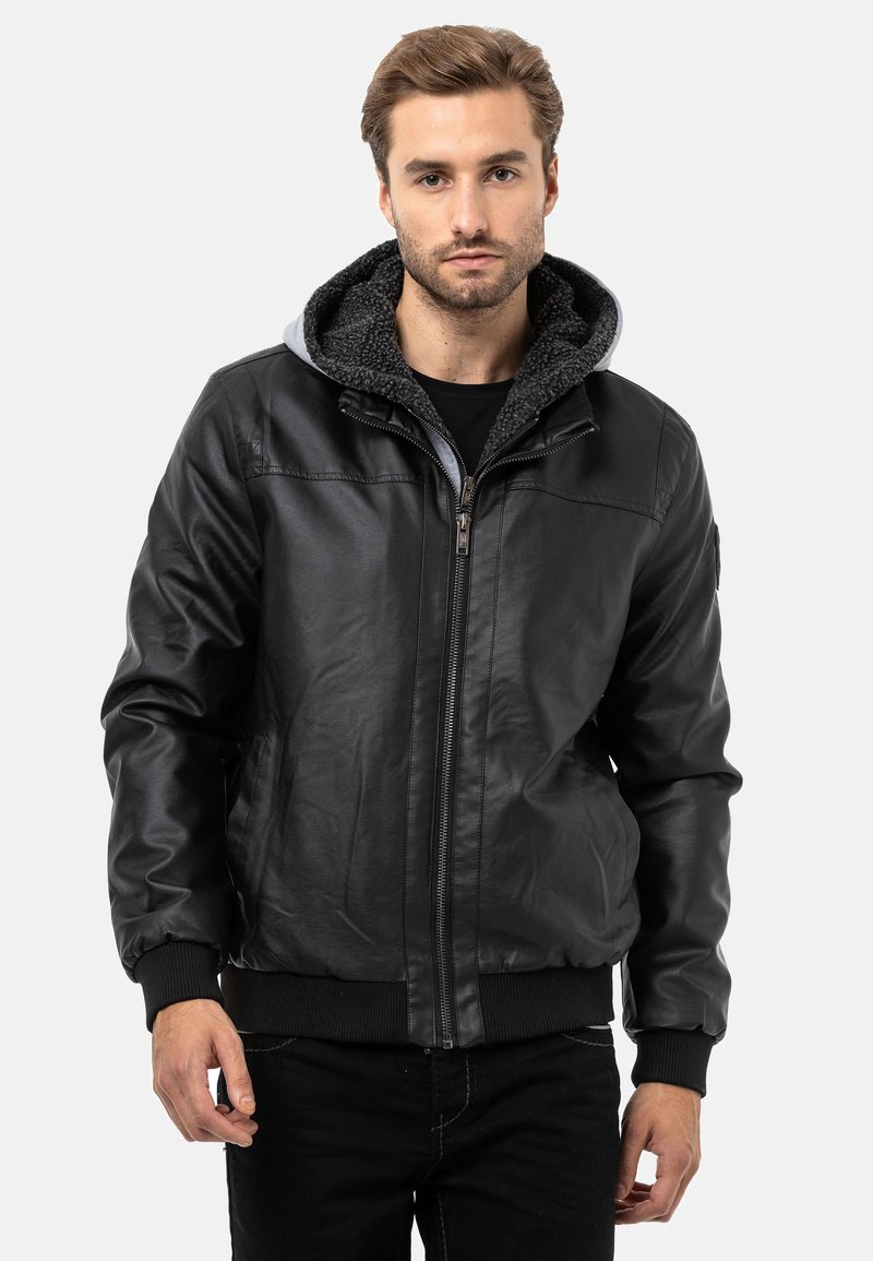 Schwarze Lederjacke mit Reißverschluss vorne, grauer Kapuze und gerippten Bündchen. Verfügt über eine glatte Außenfläche und ein weiches Innenfutter für Wärme.