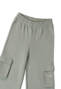 Jasnoszare spodnie cargo z elastyczną talią i kieszeniami z klapkami, jedna kieszeń z napisem "MUZYKA TO MAGIA" małymi białymi literami.