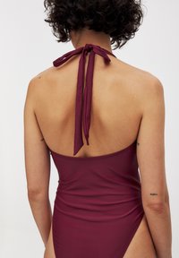 Bordeauxbaddräkt med halterneckband, snygg design, låg rygg och högskurna ben. Slätt tyg med minimalistisk stil och inga synliga mönster.