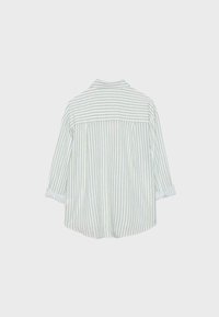 Chemise à manches longues avec des rayures beiges et blanches verticales, poignets pliés et un empiècement avec des rayures horizontales dans le haut du dos.