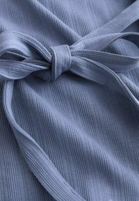 Light blue fabric with a textured ribbed pattern, featuring a tied bow detail. Smooth surface with consistent lines and subtle shine.
