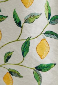 Motif de citrons et de feuilles sur un tissu blanc texturé. Comprend des citrons jaunes vibrants et des feuilles vertes entrelacées dans un design fluide.