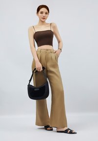 Brun ribbet crop top, beige høj talje brede bukser, sort skuldertaske og sorte slidesandaler. Minimalistisk design med rene linjer.