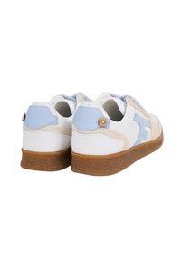 Un paio di sneakers bianche con dettagli azzurri e beige, suole in gomma di cocco e un piccolo bottone in legno sul tallone.
