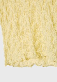 Tissu en dentelle jaune avec un motif texturé, présentant un bord festonné et des détails complexes partout. Matériau doux et léger.