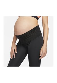 Leggings neri per gravidanza con una cintura ampia e ripiegata; design aderente; texture liscia; adatti per un indossare confortevole durante la gravidanza.