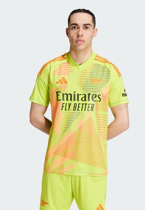 Neon keltainen urheilupaita, jossa on geometrisia kuvioita oranssina ja vihreänä, ja "Emirates Fly Better" painettuna näkyvästi etuosassa.