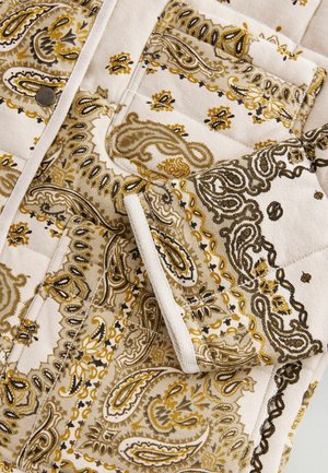 Quilted fabric with a beige base, featuring intricate gold and black paisley patterns. Includes a visible pocket and metal button detail.