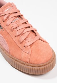 Baskets en suède rose avec bout rond, tige texturée et semelle en caoutchouc surélevée. Équipées d'un système de laçage et d'un logo discret sur le côté.