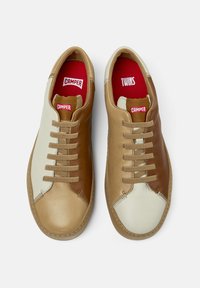 Sneaker in pelle marrone e crema con sei occhielli per i lacci beige, solette rosse con il marchio "TWINS" e "CAMPER", e cuciture a contrasto.