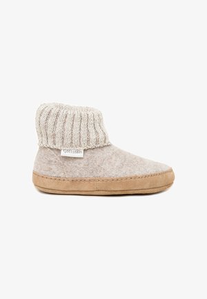 Zachte beige wollen pantoffel met een bruine suède zool en geribbelde gebreide manchet, met een klein wit label aan de zijkant.