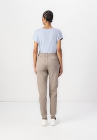 Ljusblå kortärmad topp i kombination med ljusbeige byxor med elastisk midja, som har två bakfickor, stylad med vita sneakers.