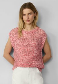 Rood en witte gestructureerde top met korte mouwen en een ronde halslijn, in een ontspannen pasvorm, gecombineerd met witte pantalons, tegen een grijze achtergrond.