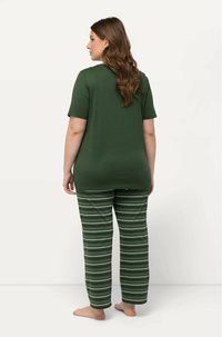 Groen T-shirt met korte mouwen, gecombineerd met gestreepte broek in tinten groen en wit. Ontspannen pasvorm, zachte stof en casual ontwerp.