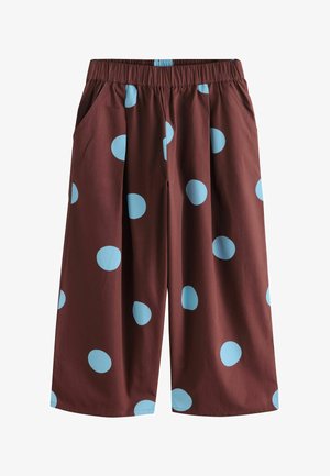 Pantalones marrones de corte holgado con grandes lunares azul claro y cintura elástica con bolsillos laterales.