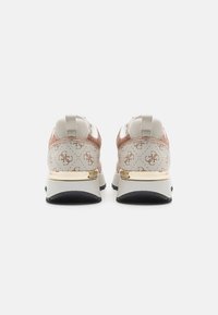 Scarpe sportive con una tomaia leggera beige testurizzata con un accento dorato, un retro con motivo e una grossa intersuola bianca. Suola in gomma nera.