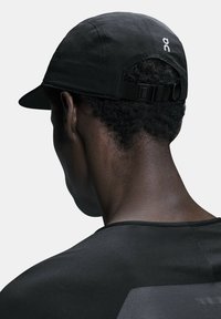Black running cap with a curved brim, made from lightweight fabric. Features adjustable strap at the back and minimal logo detail.