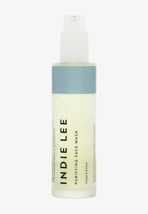 Bouteille transparente de nettoyant pour le visage purifiant INDIE LEE, avec un capuchon bleu clair, arborant un texte noir en gras, et un liquide jaunâtre à l'intérieur.