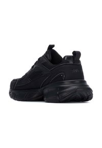 Zapatillas deportivas negras con parte superior de malla texturizada, collar acolchado y suela de goma gruesa que presenta patrones de tracción distintos y una lengüeta.
