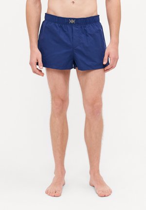 Marineblaue Badeshorts mit einem elastischen Bund und silbernen Details an der Vorderseite. Hergestellt aus leichtem Stoff bieten sie eine lockere Passform.