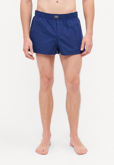 Marineblaue Badeshorts mit einem elastischen Bund und silbernen Details an der Vorderseite. Hergestellt aus leichtem Stoff bieten sie eine lockere Passform.