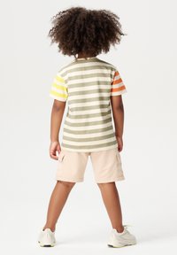 Gestreepte t-shirt in aardetinten met gele, oranje en groene mouwen, gecombineerd met beige shorts. Heeft een relaxte pasvorm en een zachte textuur.