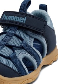 Niebieskie sandały dziecięce wykonane z siateczki i gumy, z zapięciem na rzep, otwartym fasonem oraz jasnobrązową podeszwą.