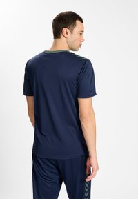 Marine sportshirt met korte mouwen, groene accenten op de kraag en een visgraatpatroon langs de zijkant. Lichtgewicht, vochtregulerende stof.