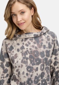 Sweter w leopardzie w wzór z miękkiej, teksturowanej tkaniny, z szerokim kołnierzem i luźnym krojem w odcieniach beżu i szarości.