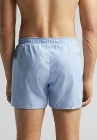 Blue and white striped swim shorts with an elastic waistband and a relaxed fit, featuring a smooth texture and cut above the knee.
