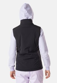 Schwarz ärmellose Weste mit hohem Kragen, getragen über einem hellgrauen Langarm-Hoodie. Glatter Stoff, minimalistisches Design, keine sichtbaren Beschläge.