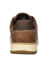 Zapatilla de cuero marrón con un collar acolchado, media suela de color crema con un patrón texturizado y un pequeño logo en el talón.