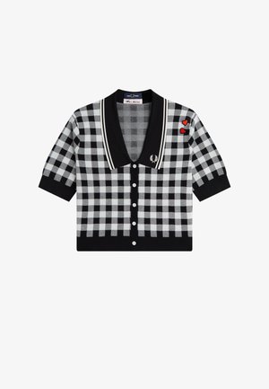 Cárdigan de manga corta con patrón de cuadros en blanco y negro, con cuello negro, botones blancos, dos parches rojos en forma de corazón y un logo bordado en blanco en el pecho.