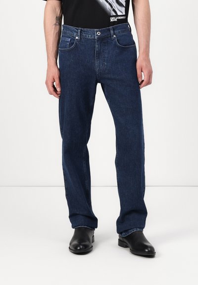 Jean en denim bleu marine avec une coupe droite, doté de poches avant et d'une fermeture à bouton. Le tissu présente une finition légèrement texturée.