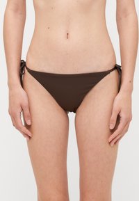 Brun bikinitrosa i mjukt tyg, med sidodragkedjor. Triangelform med minimal täckning, designad för komfort och passform.