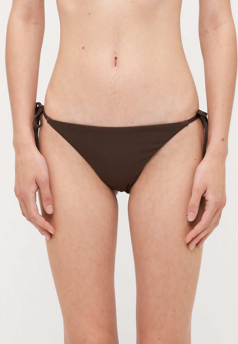 Brun bikinitrosa i mjukt tyg, med sidodragkedjor. Triangelform med minimal täckning, designad för komfort och passform.
