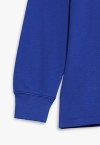 Modrá bavlněná košile s dlouhým rukávem, s žebrovaným manžetovým zakončením a hladkou texturou, se jednoduchým designem a jednobarevným provedením.