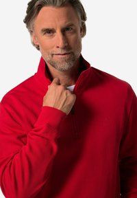 Roter Pullover aus weichem Material, mit einem halben Reißverschluss am Kragen, gerippten Bündchen und einem Logo-Akzent auf der Brust, angenehme Textur und taillierte Passform.