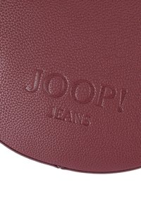 Burgundská texturovaná kožená plocha s vytlačeným logem značky "JOOP! JEANS".