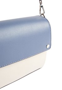 Niebieska i biała torba z sztucznej skóry o teksturowanym wykończeniu, z okrągłym klapkiem i srebrnymi akcentami. Czysty design z kontrastującymi kolorami.