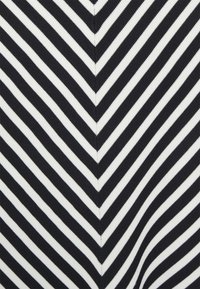 Černobílé diagonální pruhy tvořící symetrický chevron vzor se středním vertikálním švem.